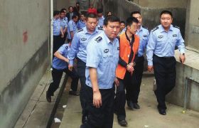 伍涛在公安民警的看押下指认现 原标题:湖南法警入室抢劫杀人后